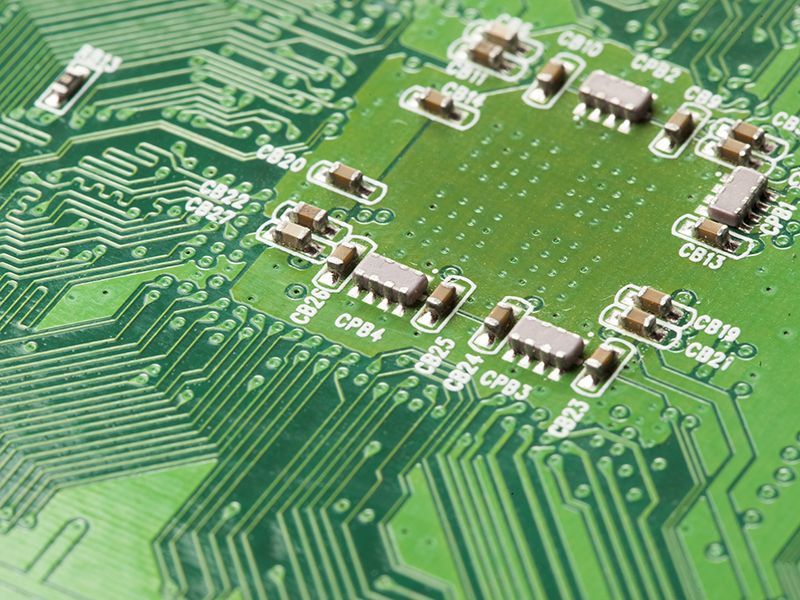 Placa de circuito eléctrico verde con microchips, conductores y transistores